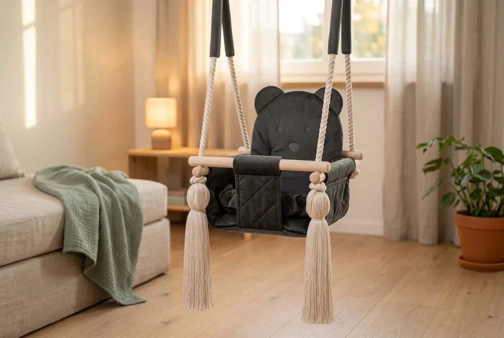 Dunkelgraue Samtschaukel mit Baermotiv in einem warm beleuchteten Kinderzimmer mit Eichenboden